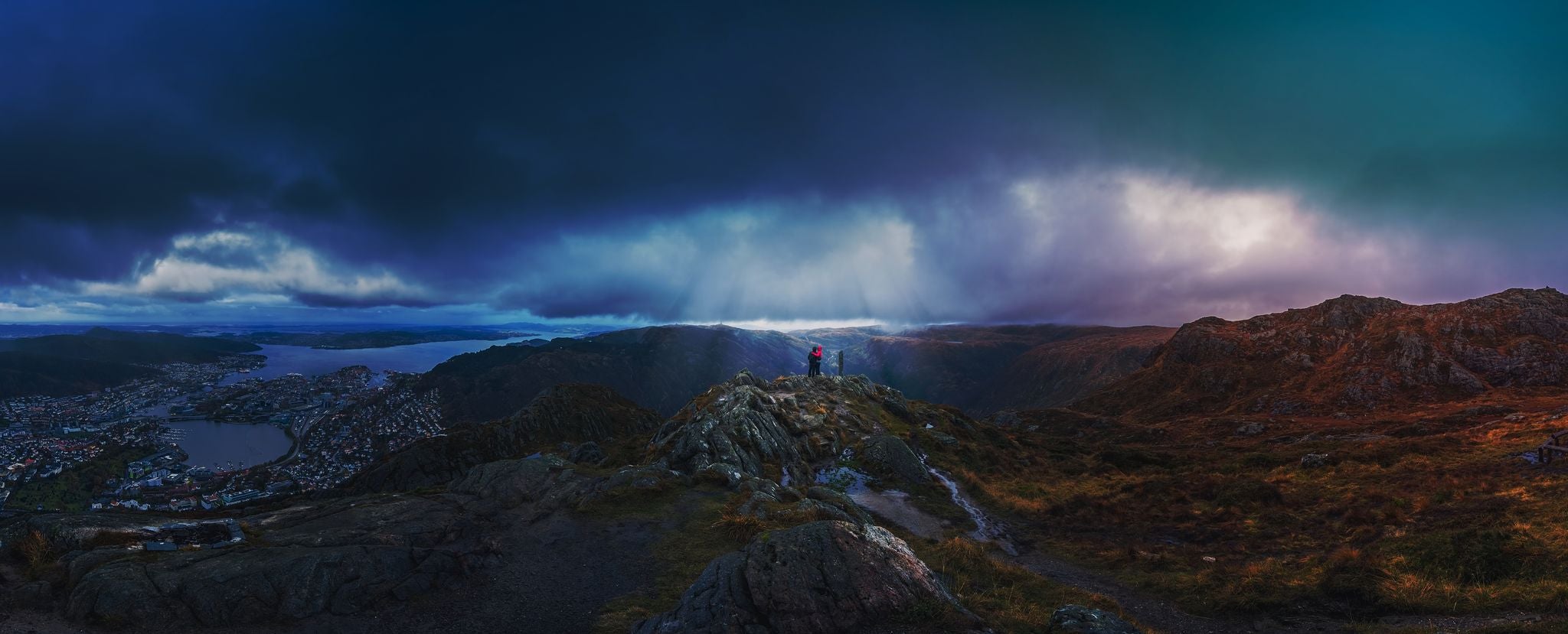 Unidentifiable tourists standing on the top of mount Ulriken in Bergen in loving embrace, Norway