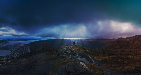 Unidentifiable tourists standing on the top of mount Ulriken in Bergen in loving embrace, Norway
