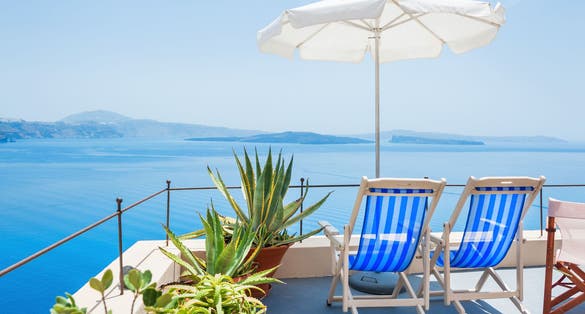 Photo of sunbeds looking to the amazing view of Santorini, Greece.
