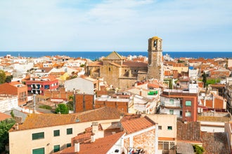 photo of over the roofs of old town Malgrat de Mar (Spain) from the hill with Mediterranean sea in the background and the Cathedral of the Coast in the middle.