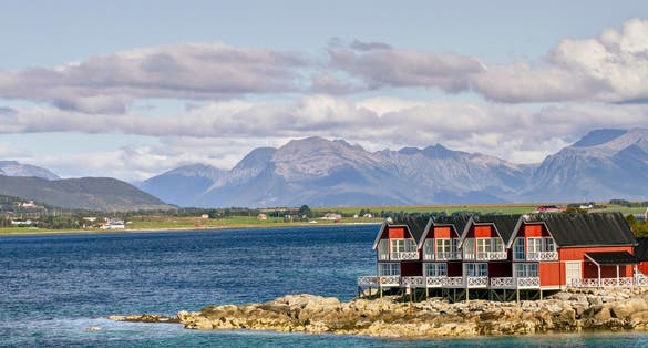 photo of view of Entrance from sea into fishing village of Stokmarknes, Norway, with mountains behind.