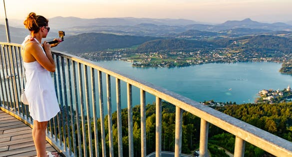 Photo of girl standing on deck of Pyramidenkogel viewing tower in Carinthia with view at lake and Klagenfurt city.