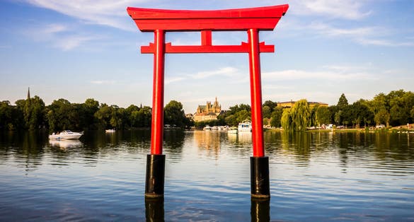 Photo of the Japanese torii in the Plan d'Eau Saint-Symphorien, Saulcy, Metz, France, with the Gothic cathedral of Saint Stephen in the background.