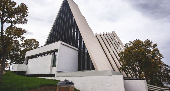 View of Tromso, with cathedral, Tromso Bridge, Tromsoya island, embankment and scenery beyond the city, Troms og Finnmark county, Norway, summer day.