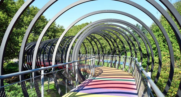 Photo of slinky springs bridge at Oberhausen Kaisergarten, abstract bridge with metal rings and multicolored floor, Germany.