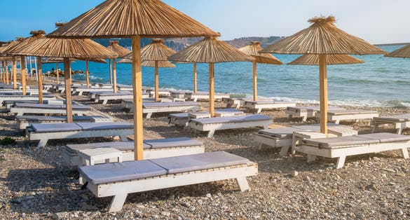 Photo of beach with sun umbrellas and sunbeds in town Bar in Montenegro on Adriatic sea.