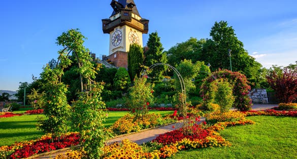 Photo of The medieval Clock tower Uhrturm in flower garden on Shlossberg hill, Graz, Austria.