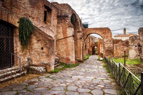 Old street on Roman Forum by Palatine Hill (Palatino), Rome, Italy. Scenery of Ancient buildings, tourist attractions of Rome. Cobbled road, walkway with ruins in Roma city. Theme of travel in Rome.