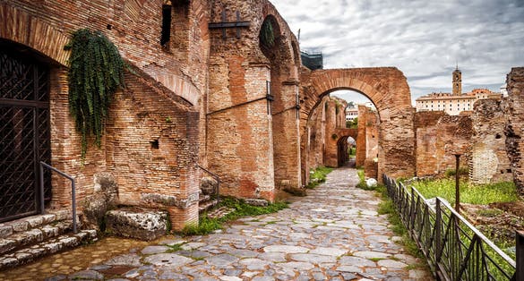Old street on Roman Forum by Palatine Hill (Palatino), Rome, Italy. Scenery of Ancient buildings, tourist attractions of Rome. Cobbled road, walkway with ruins in Roma city. Theme of travel in Rome.