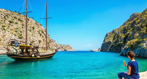 Photo of lady eating icecream on bank of cosy port on Greek Island, Kos.