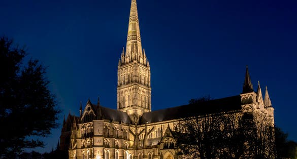 Photo of Salisbury Cathedral illuminated at night, formally known as the Cathedral Church of the Blessed Virgin Mary, an Anglican cathedral in Salisbury, England.