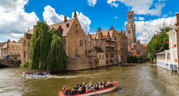 Photo of canal in Bruges and famous Belfry tower on the background in a beautiful summer day, Belgium.
