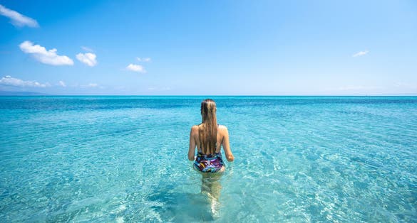 A girl walking in the water in La Pelosa beach, Sassari Province, Sardinia, Italy