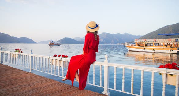 Photo of beautiful young girl in a red dress and a straw hat ,beautiful view of Marmaris, Turkey.