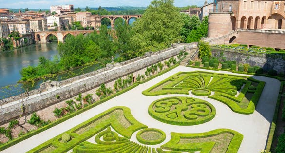 Photo of beautiful view of the Tarn River and a garden with flowers in the Toulouse-Lautrec museum in Albi in France.