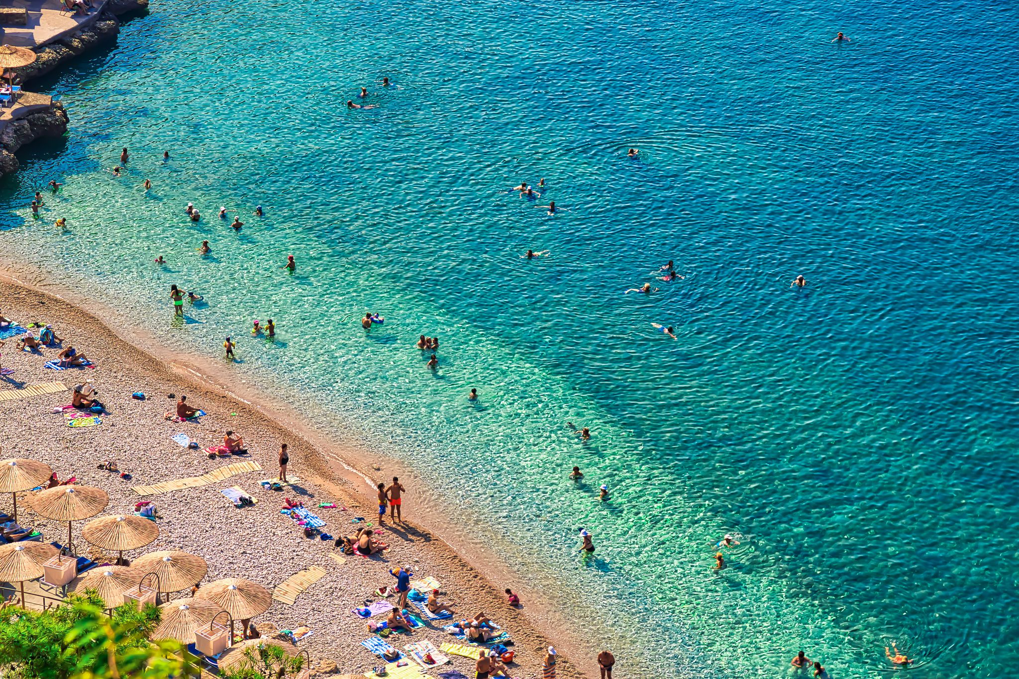 Photo of people on the Nafplio beautiful beach with clear water and blue sky, in the Peloponnese peninsula in Greece.