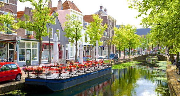 Picturesque Delft cityscape view with Eastern Gate Oostport and canal with cars and bicycles parked along. Delft, Netherlands's