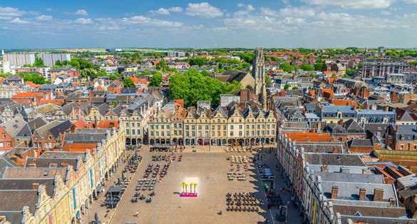 Aerial panoramic view of Arras city historical centre, Heroes Square with old Flemish-Baroque-style townhouses and John the Baptist catholic church, blue sky in summer day, Artois, Hauts-de-France