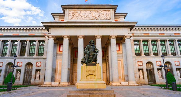 Photo of entrance to the Prado Museum in Madrid at this time, a sunny day with blue skies and clouds.