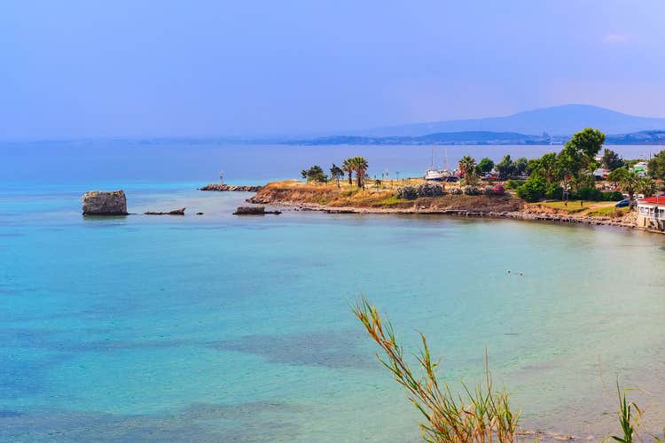 Photo of turquoise beautiful beach and old port of Nea Potidea or Nea Poteidea in peninsula Kassandra, Chalkidiki, Greece.