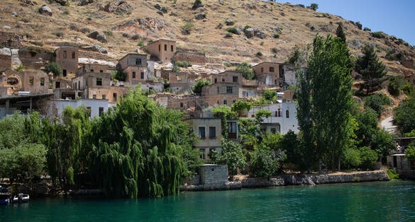 PHOTO OF VIEW OF Halfeti, the sunken village at Şanlıurfa, Turkey. Popular touristic attraction at Anatolia. Traditional village under the waters of Birecik Dam. Mosque minaret under the lake, Şanlıurfa, Turkey.