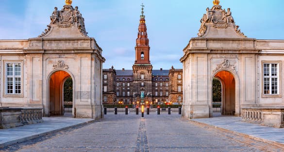 Photo of the main entrance to Christiansborg with the two Rococo pavilions on each side of the Marble Bridge during morning blue hour, Copenhagen, capital of Denmark.