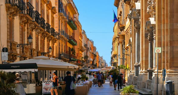  View of the central street corso Vittorio Emanuele with people and old buildings in historical center of Trapani, Sicily, Italy.