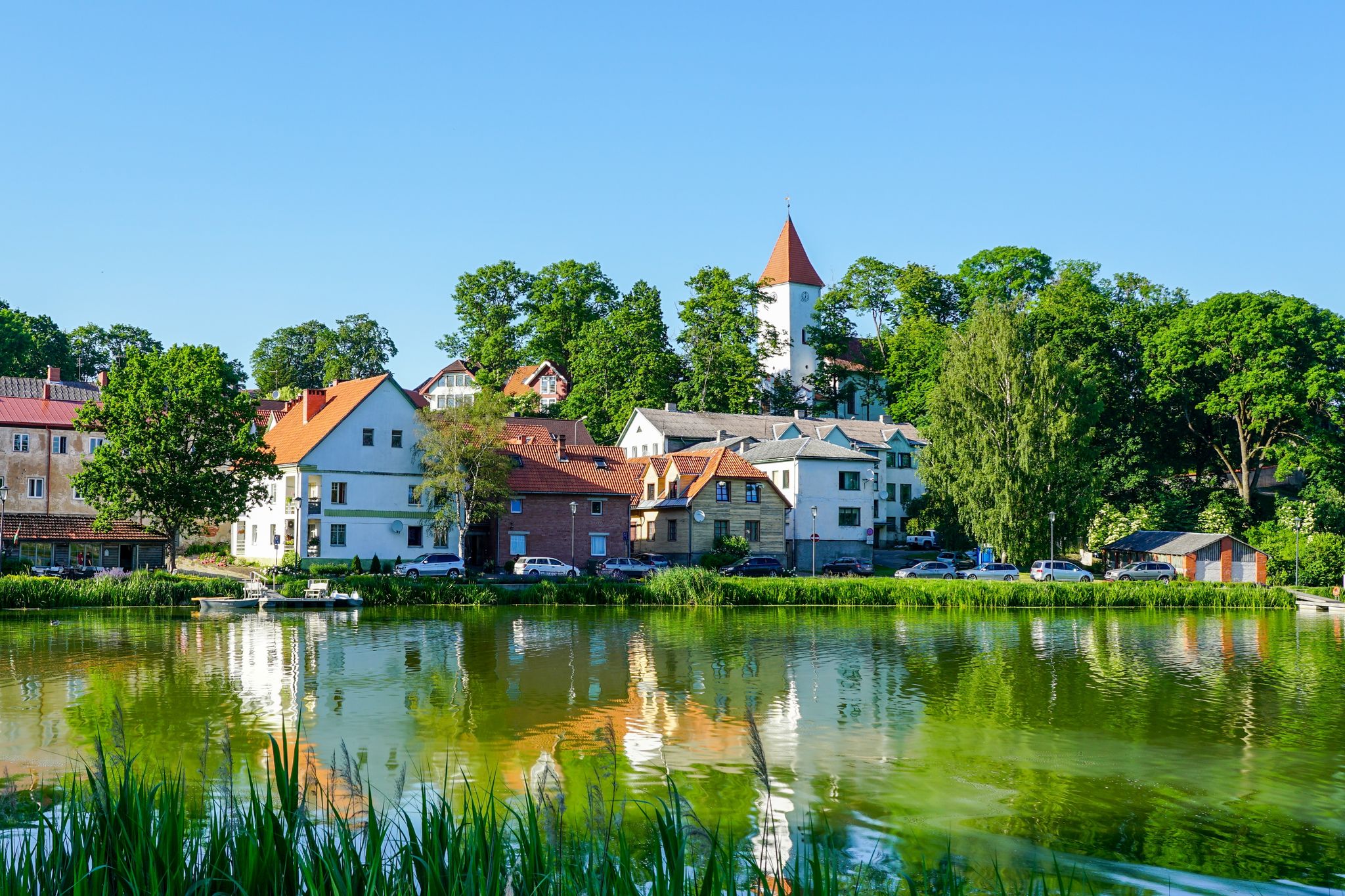 Photo of beautiful old town houses and church panorama with lake reflection in summer morning in Talsi, Latvia.