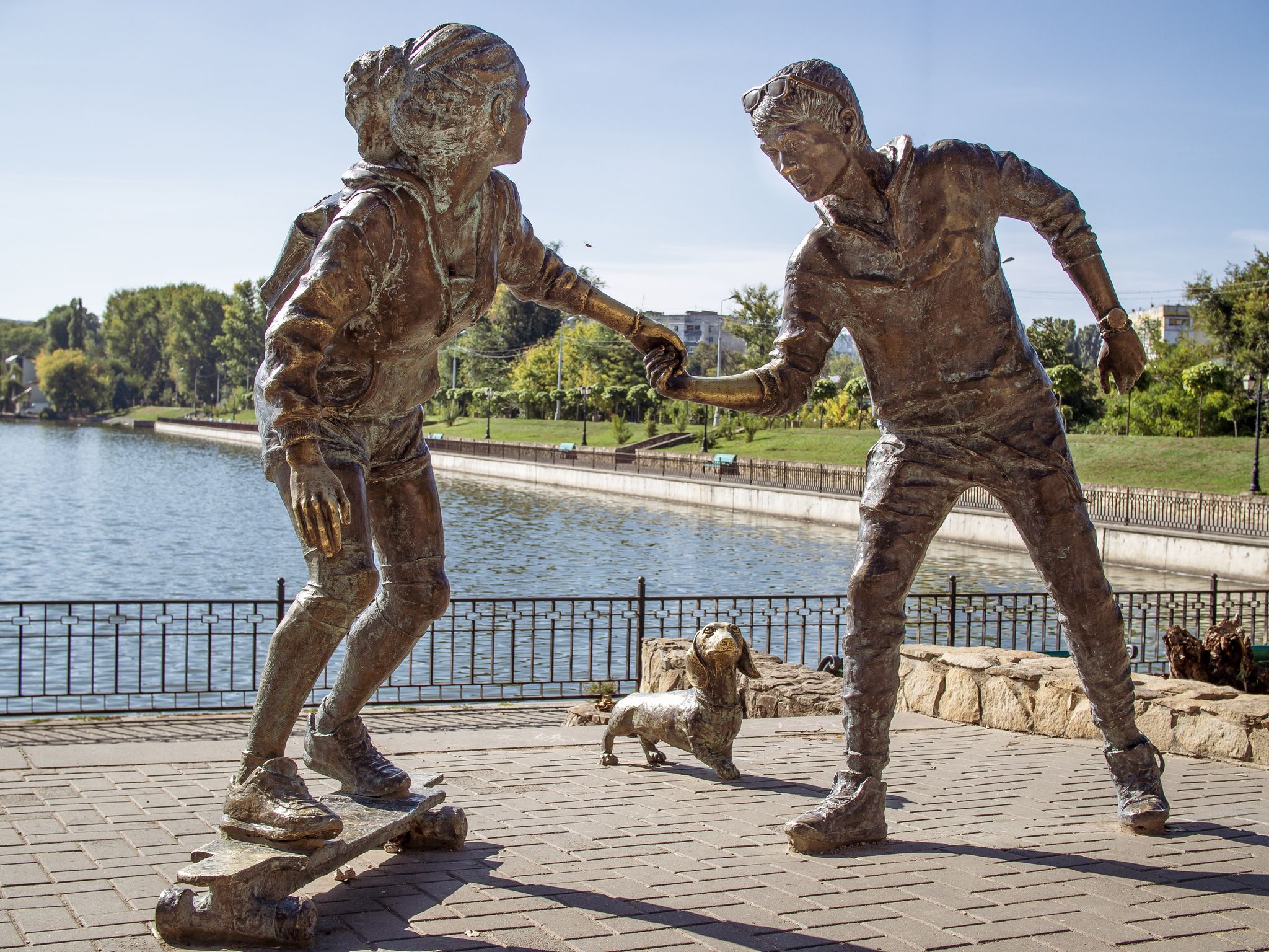 photo of Chisinau, Moldova-October 2, 2018: Young couple on skateboard with Basset Hound dog sculpture by petru glavan in valea morilor park.