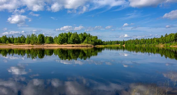 Photo of  Ivalo: Panorama view of pure rural Finnish nature with calm lake water, cloud reflections.