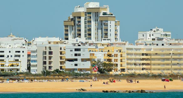 Photo of city buildings and clear blue sky background in Quarteira Beach, Algarve, Portugal.