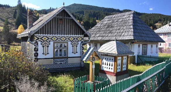 Trinity, fountain and traditional painted houses from Ciocanesti village, Suceava, Romania.