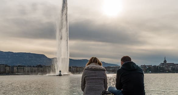Photo of couple sitting on the wooden Jetty at Bains des Paquis, Switzerland.