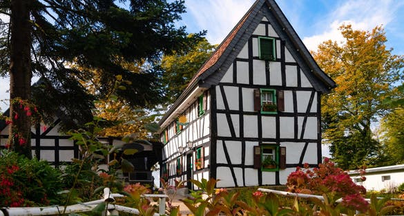 photo of view of Historic truss house and monument in Rhine Valley near Bonn and Königswinter Germany on “Drachenfels“. Traditional architecture with black and white half timbering in idyllic garden in autumn season.