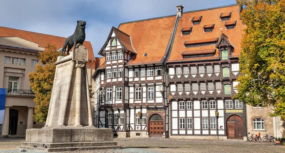 Photo of Statue of Lion and old half-timbered building on Burgplatz square in Braunschweig, Germany.