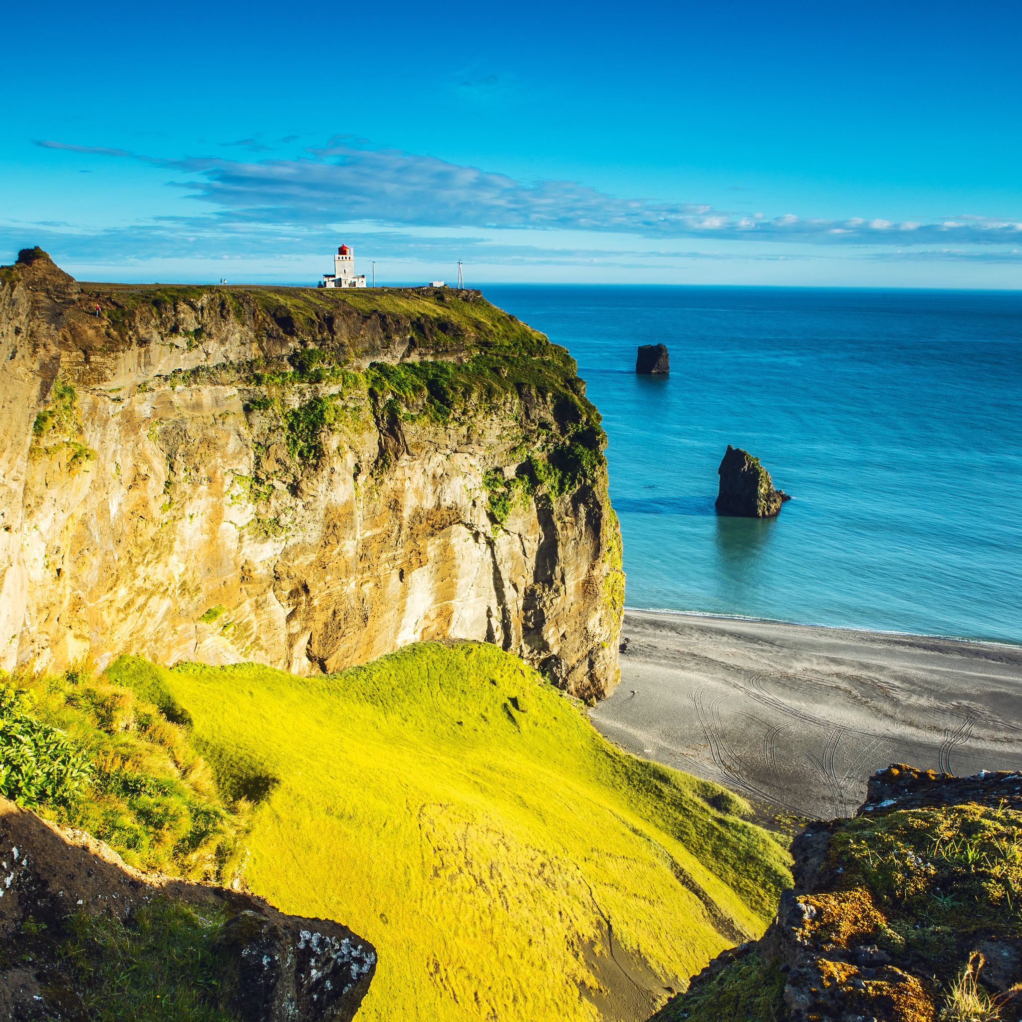 photo of a beautiful view on an ocean and a cliff with a dyrhólaey lighthouse on the top in Iceland.