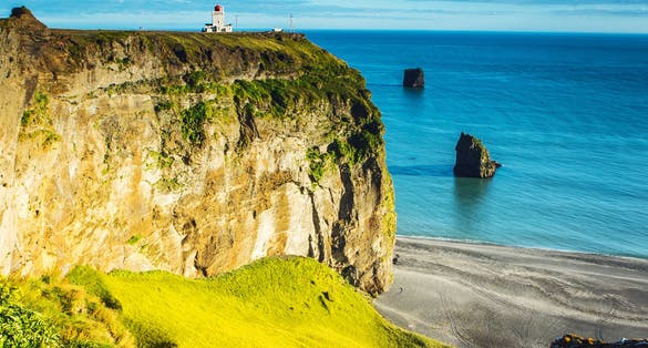 photo of a beautiful view on an ocean and a cliff with a dyrhólaey lighthouse on the top in Iceland.