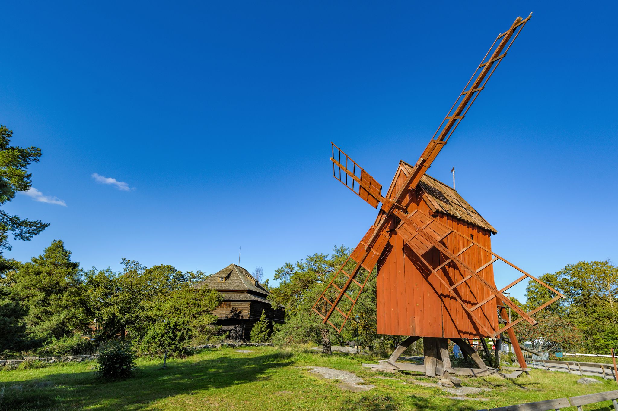 Photo of an old weathered wooden windmill painted in traditional falun red in the Skansen (the Sconce) open-air Museum in Stockholm, Sweden.