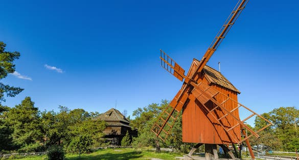 Photo of an old weathered wooden windmill painted in traditional falun red in the Skansen (the Sconce) open-air Museum in Stockholm, Sweden.