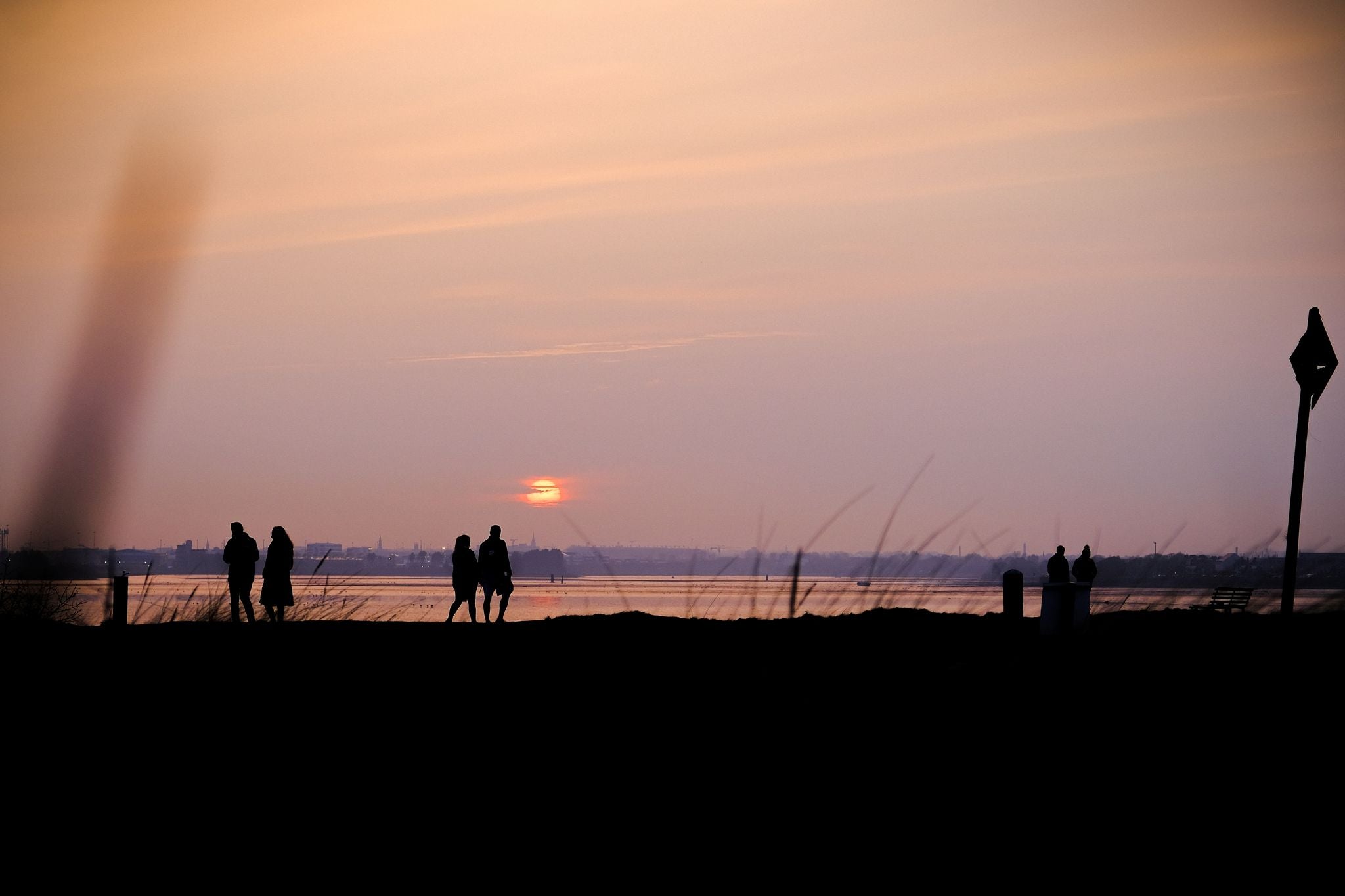 photo of A beautiful landscape of the sunset at the beach and people walking in Bull Island, Ireland