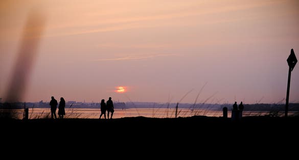 photo of A beautiful landscape of the sunset at the beach and people walking in Bull Island, Ireland