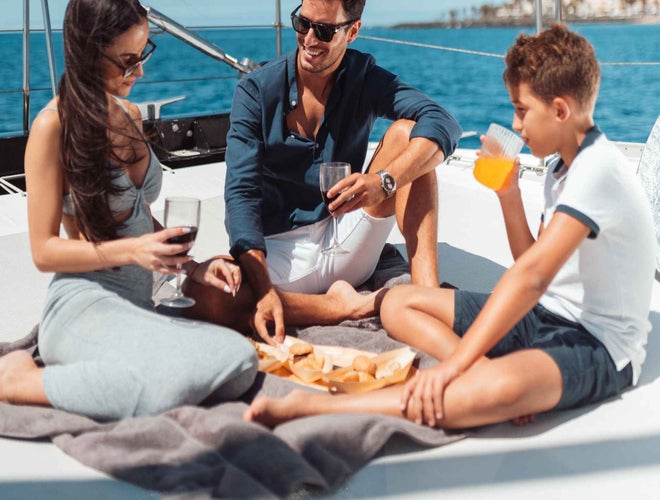 A family enjoys a picnic on a yacht, with the man and woman drinking wine and the boy sipping orange juice..jpg