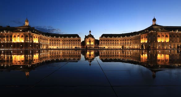 photo of Place de la Bourse in Bordeaux with its reflections in water mirror in a beautiful summer night in France.