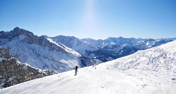 Photo of snowboarder on the slopes high in the Alps between Germany and Austria with snow, blue sky and sunlight.