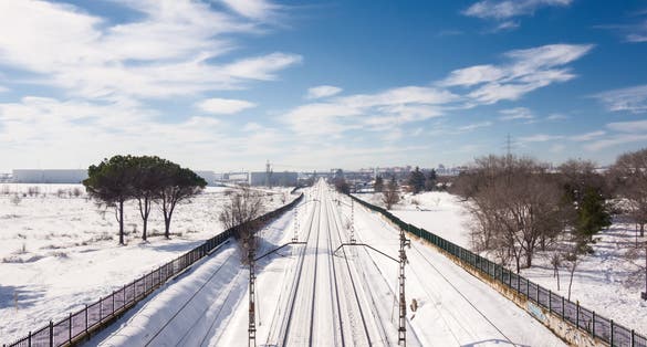 Snowy train tracks in Coslada on a cold winter's day, on a blue sky morning with some clouds.