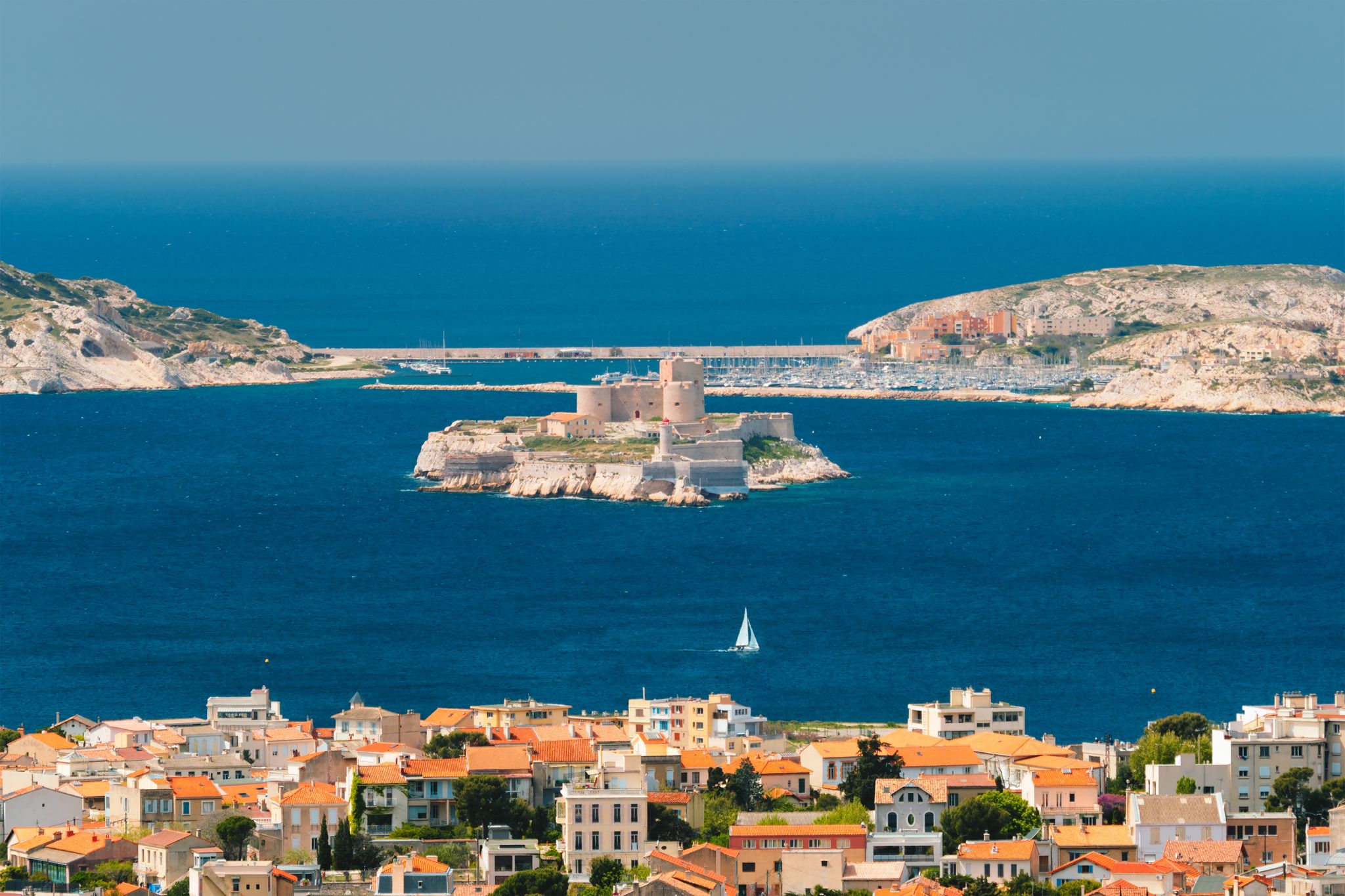photo of Marseille town and Chateau d'If castle famous historical fortress and prison on island in Marseille Bay with yacht in sea. Marseille, France.