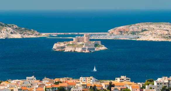 photo of Marseille town and Chateau d'If castle famous historical fortress and prison on island in Marseille Bay with yacht in sea. Marseille, France.