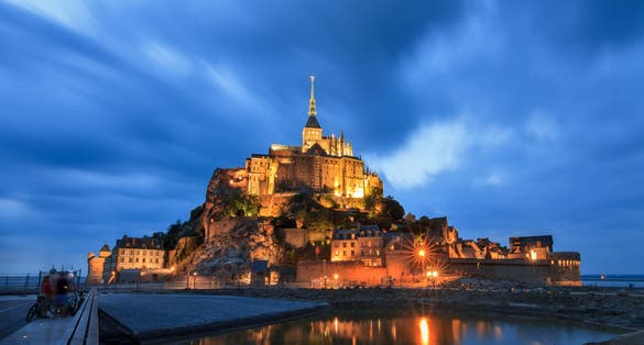 Photo of beautiful view of historic landmark Le Mont Saint-Michel at night in Normandy, France.