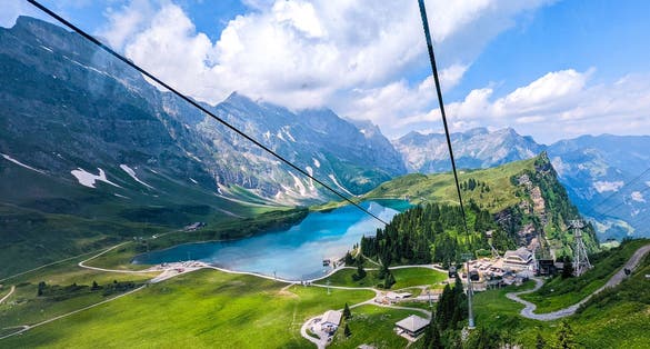 photo of breathtaking view of a serene lake nestled atop Mount Titlis. The lake itself is calm and tranquil, with clear, still waters that reflect the surrounding mountains and sky in Switzerland.