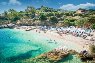 Photo of tourists relaxing on beautiful beach of Kasiopi in the north area of Corfu Island, Greece.